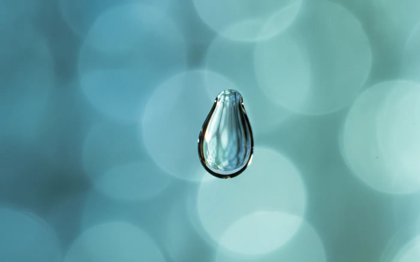 Macro de una gota de agua sobre cristal, con fondo azul desenfocado